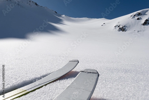 Fototapeta Single ski tourer ascending towards a snow covered ridge