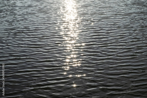 Fototapeta Sun glare on the water's surface, selective focus. Relaxing landscape with sunlight reflections.