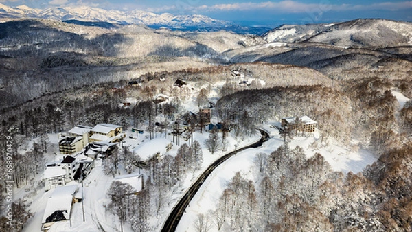 Obraz Winding road through a remote snowy mountain village on a sunny winter day