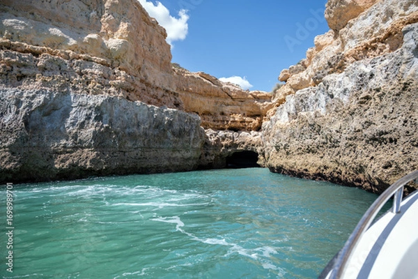 Fototapeta View of Benagil caves and cliffs on turquiose ocean water as seen from a tour boat. Rock texture and dramatic color nature geology landscape rock formation Algarve travel tourism background copy space