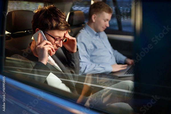 Fototapeta working night-business woman use smartphone in the car.