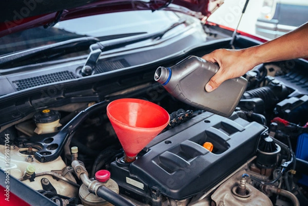 Fototapeta technician changing engine oil and performing vehicle service in a garage, professional auto mechanic work, tools and car parts, clean and organized workshop