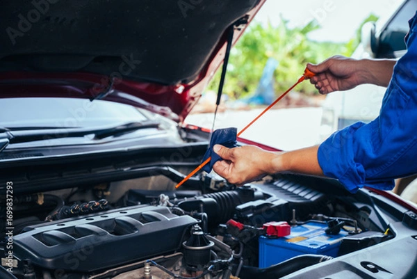 Fototapeta technician changing engine oil and performing vehicle service in a garage, professional auto mechanic work, tools and car parts, clean and organized workshop