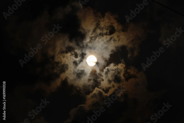 Fototapeta The sun during the day is surrounded by clouds with a dark and yellowish color concept, some of which appear to form a silhouette