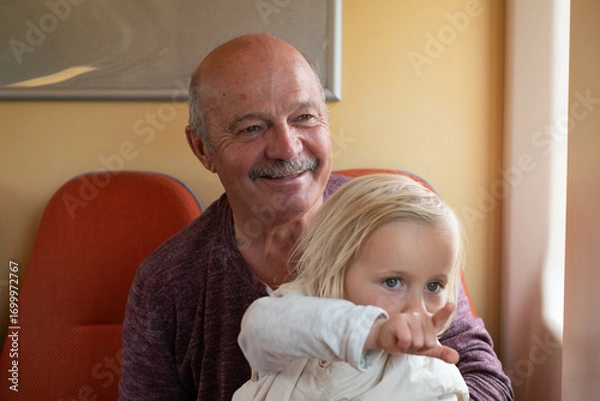 Fototapeta grandfather with granddaughter riding on train and looking out the window
