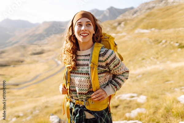 Obraz Young woman with hiking backpack enjoying hiking in mountains. Hiker enjoying mountain landscape and feeling freedom at sunset. Adventure concept, hiker. Active lifestyle.