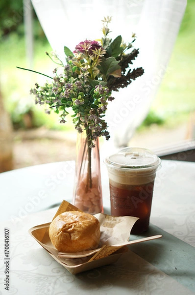 Obraz Delicious snack with refreshing iced coffee on the table with decorative flowers. The scene evokes a sense of leisure and comfort, perfect for a relaxing break