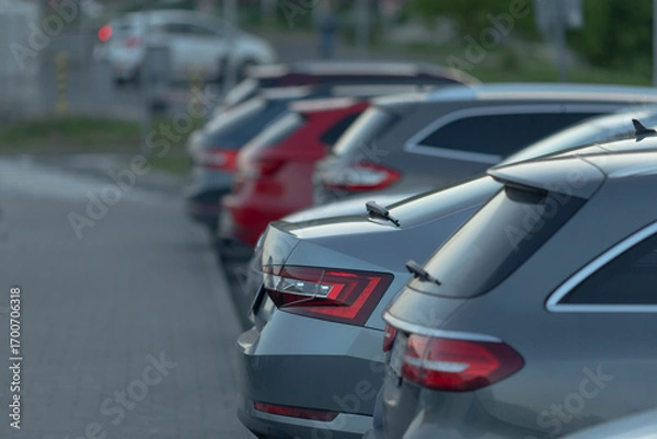 Fototapeta A lineup of several gray and red SUVs is parked in the midst of a bustling urban environment, showcasing city life