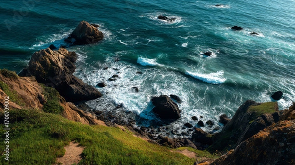 Fototapeta Scenic view of the ocean from the top of a grassy hill under clear blue sky