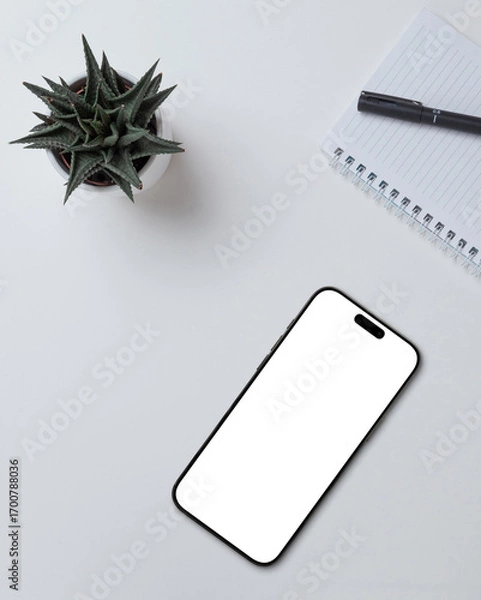 Fototapeta Smartphone mockup with blank screen on desk with notebook and plant