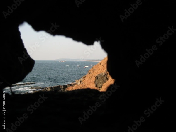 Fototapeta Coastal view through rock formation overlooking the ocean waves  