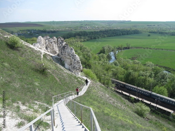 Fototapeta Scenic view of winding path down a hillside with lush greenery  