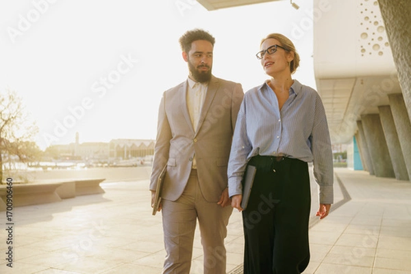 Fototapeta A group of business professionals walking together in a bustling and modern urban environment