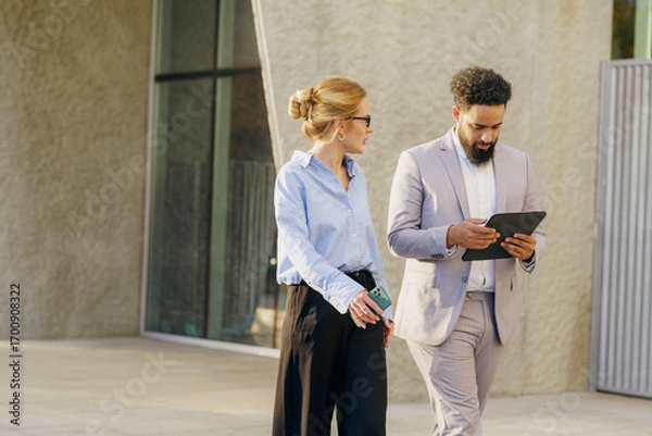 Fototapeta Business Professionals Engaging in Collaboration Outdoors Utilizing a Tablet for Tasks and Ideas