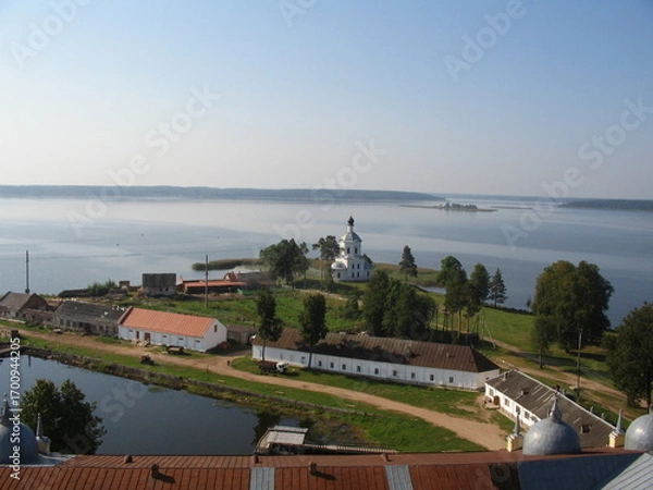 Fototapeta Scenic view of tranquil lake with church and village in summer  