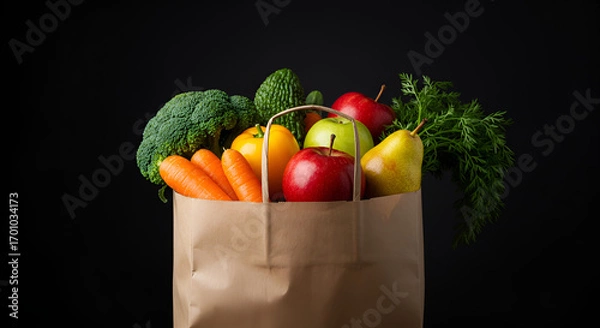 Fototapeta Paper bag filled with fresh vegetables and fruits such as broccoli, lettuce, oranges, apple, cucumber, and strawberries on black background.