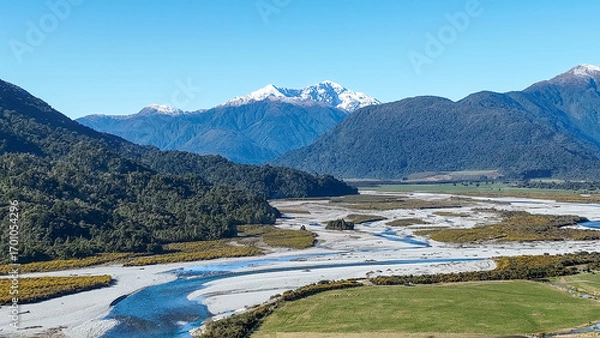 Fototapeta Surrounded by mountain ranges the Turiwhate River flows through farming fields on the road to Arthurs Pass