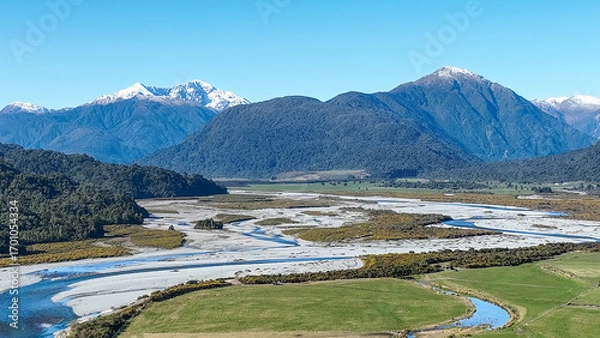 Fototapeta Surrounded by mountain ranges the Turiwhate River flows through farming fields on the road to Arthurs Pass