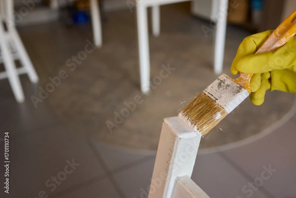 Fototapeta Engage in DIY chair restoration using a paint brush and protective gloves for the process