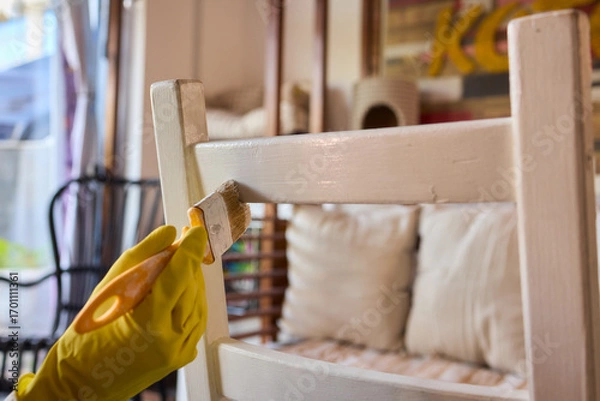 Fototapeta Engage in DIY chair restoration using a paint brush and protective gloves for the process