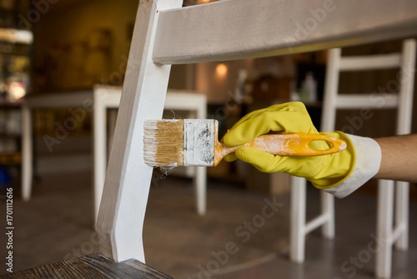 Fototapeta Engage in DIY chair restoration using a paint brush and protective gloves for the process