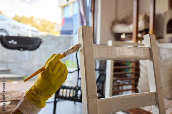 Fototapeta Engage in DIY chair restoration using a paint brush and protective gloves for the process