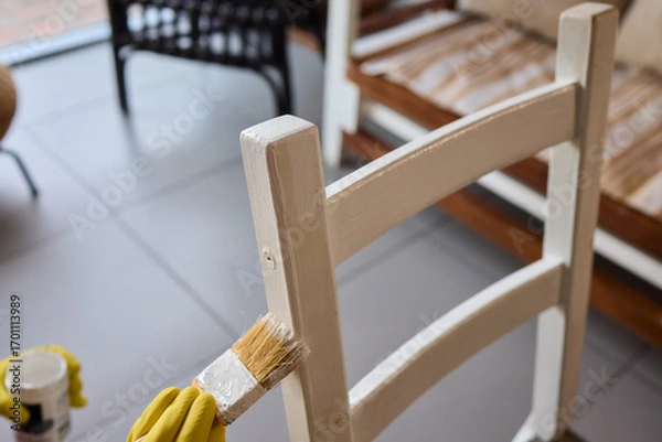 Fototapeta Engage in DIY chair restoration using a paint brush and protective gloves for the process