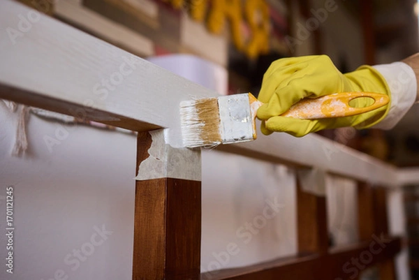 Fototapeta Engage in DIY chair restoration using a paint brush and protective gloves for the process