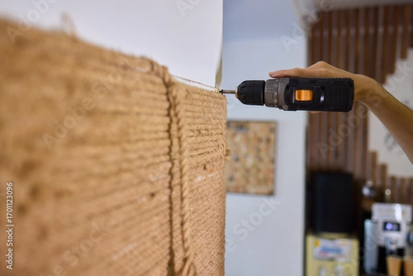 Fototapeta A skilled handyman is using a powered drill on a textured wall to enhance home improvement