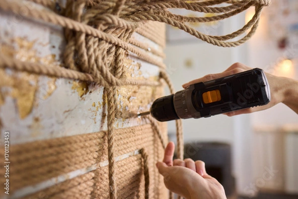 Fototapeta A skilled handyman is using a powered drill on a textured wall to enhance home improvement