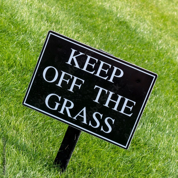 Fototapeta Keep Off the Grass sign on a nicely kept lawn in a park