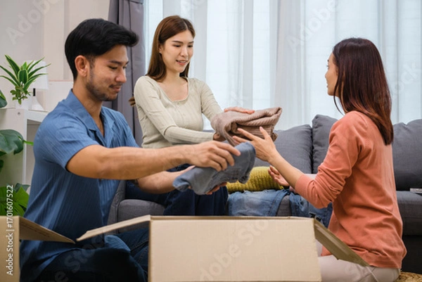 Fototapeta group of friend  sorting and packing clothes into a donation box.community support, and charitable giving