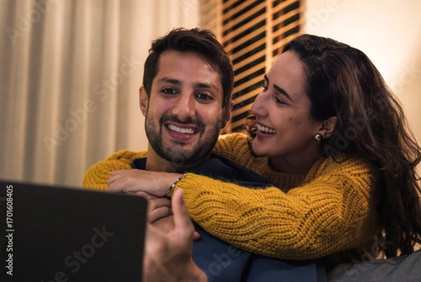 Fototapeta Couple using laptop together at home browsing streaming media and enjoying digital lifestyle connection.