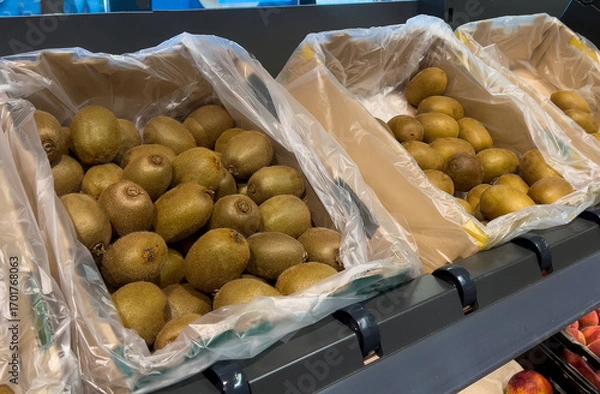Fototapeta Close up of many green and golden kiwi fruits in basket at grocery store 