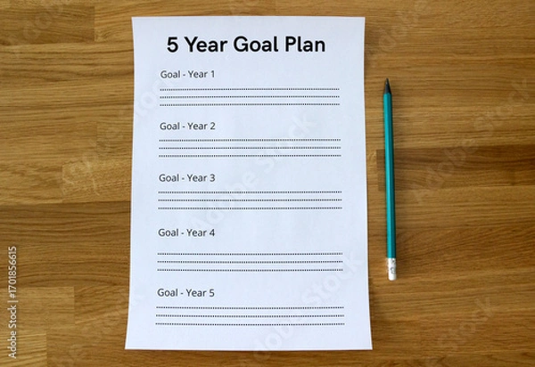 Fototapeta a sheet of paper saying '5 Year Goal Plan' lying straight on the wooden table, with a pencil parallel to the sheet