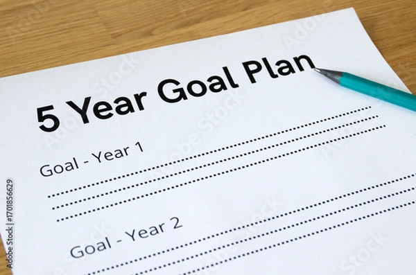 Fototapeta Extreme close-up of a sheet with a headline '5 Year Goal Plan', with a pencil pointing to the headline