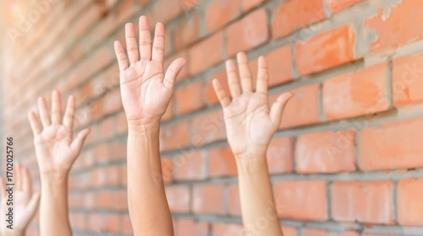 Fototapeta Multiple hands raised against a brick wall, symbolizing participation, voting, agreement, and community engagement