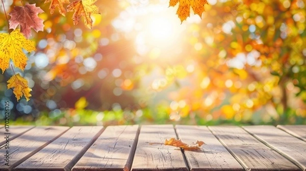 Fototapeta Sunny autumn background with empty wooden table, vibrant fall leaves, and blurred bokeh