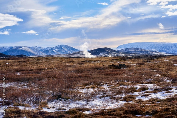 Fototapeta Landscape view of Icelands geothermal area showcasing colorful minerals, steaming vents, and barren landscapes under bright blue skies at Hverir.