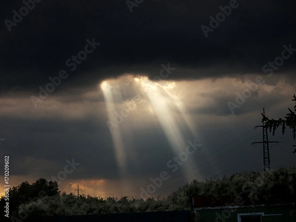 Fototapeta Sun shines through dark clouds