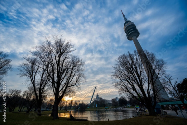 Fototapeta Olympiapark München bei Sonnenuntergang mit See, Schwänen und ikonischer Zeltdacharchitektur
