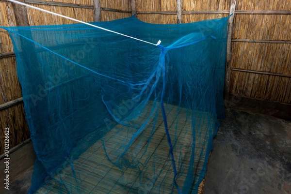 Obraz Reed-Walled African House with Blue Mosquito Net over Traditional Reed Mat