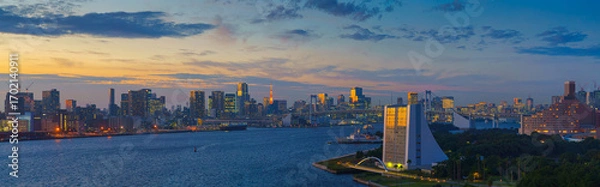 Fototapeta Tokyo, Japan - Oct 2 2024, panoramic aerial view of Tokyo Bay cityscape in background and the Rainbow Bridge, in the foreground is a part of Odaiba Island with a triangular building, Tokyo, Japan