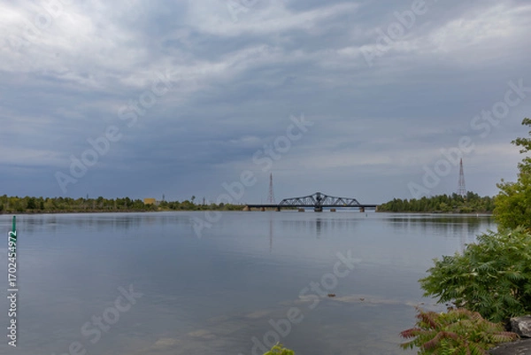 Obraz Tranquil waterfront scene at Little Current, Manitoulin Island, featuring the historic swing bridge against a serene sky and calm waters.