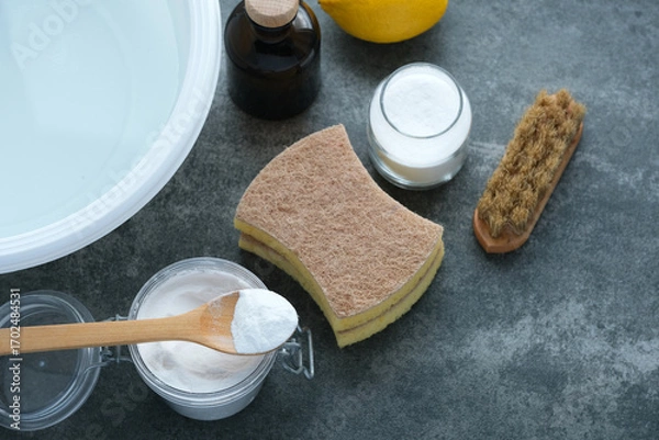 Fototapeta Cleaning supplies and natural ingredients organized on a gray surface ready for a spring cleaning session with lemon, vinegar, and baking soda. Natural cleaning products. Zero waste concept. top view.