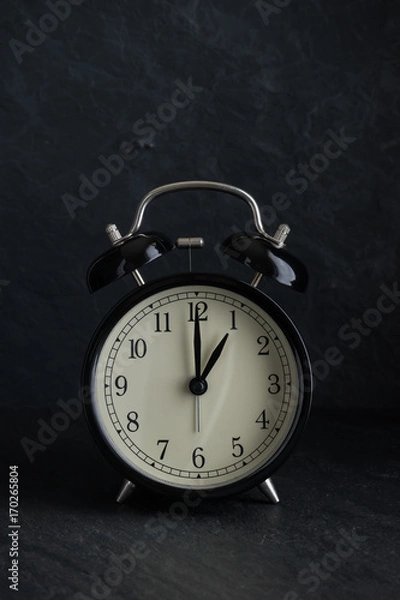 Obraz black alarm clock with stone background at one o'clock