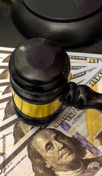 Fototapeta The judge's gavel rests on a fan of hundred-dollar bills.