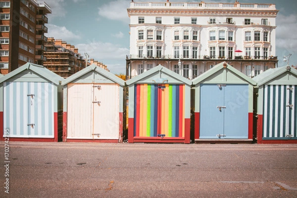 Fototapeta Colorful beach huts lined up along the promenade in Brighton during a sunny day