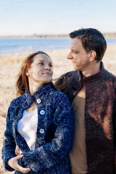 Obraz Loving couple walks on beach along sea on sunny autumn day. Weekend and lifestyle concept. Vertical photo. High quality photo