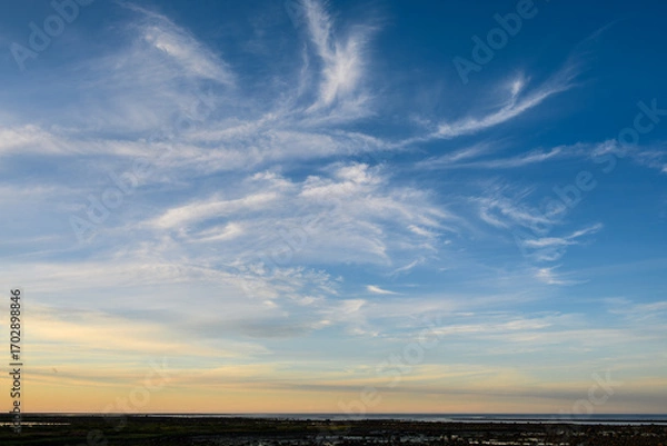 Obraz Sunset sky background over the coast of Hudson Bay, blue sky with hints of yellow and orange, and white wispy clouds
